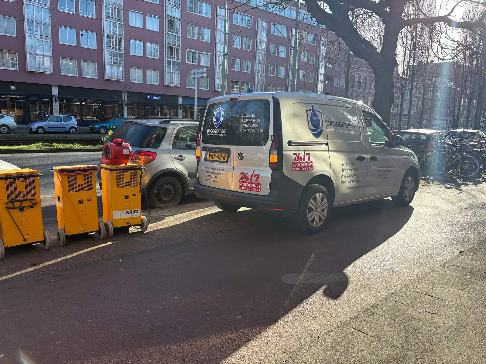 Droogexpert-servicewagen met gele bouwdrogers bij een levering